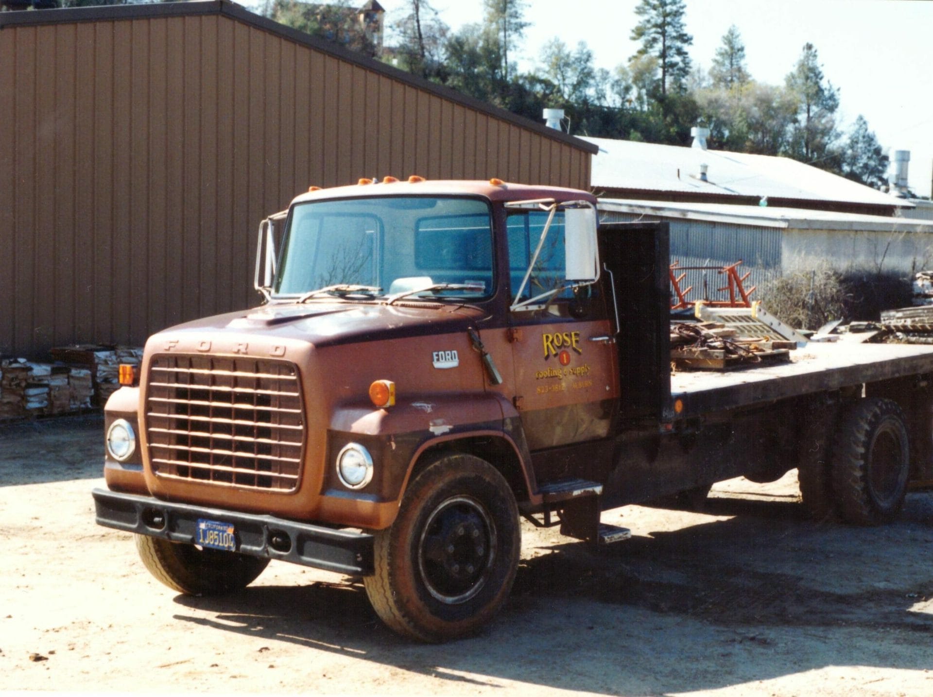 Vintage brown Ford flatbed truck in industrial yard
